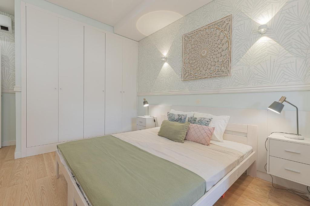a white bedroom with a large bed with two pillows at Villa Whiteloft Pool Spa Lounge in Corroios