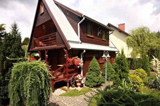 een klein huis met een veranda en een tuin bij Domek Myśliwski Wilkasy Zalesie in Wilkasy
