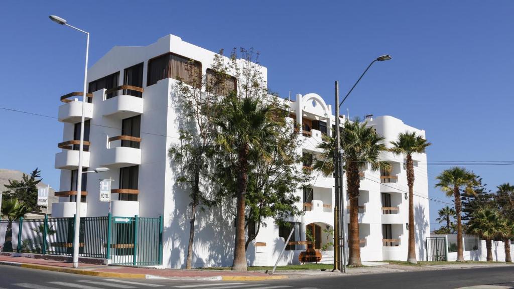 un edificio blanco con palmeras delante en Hotel Mejillones, en Mejillones