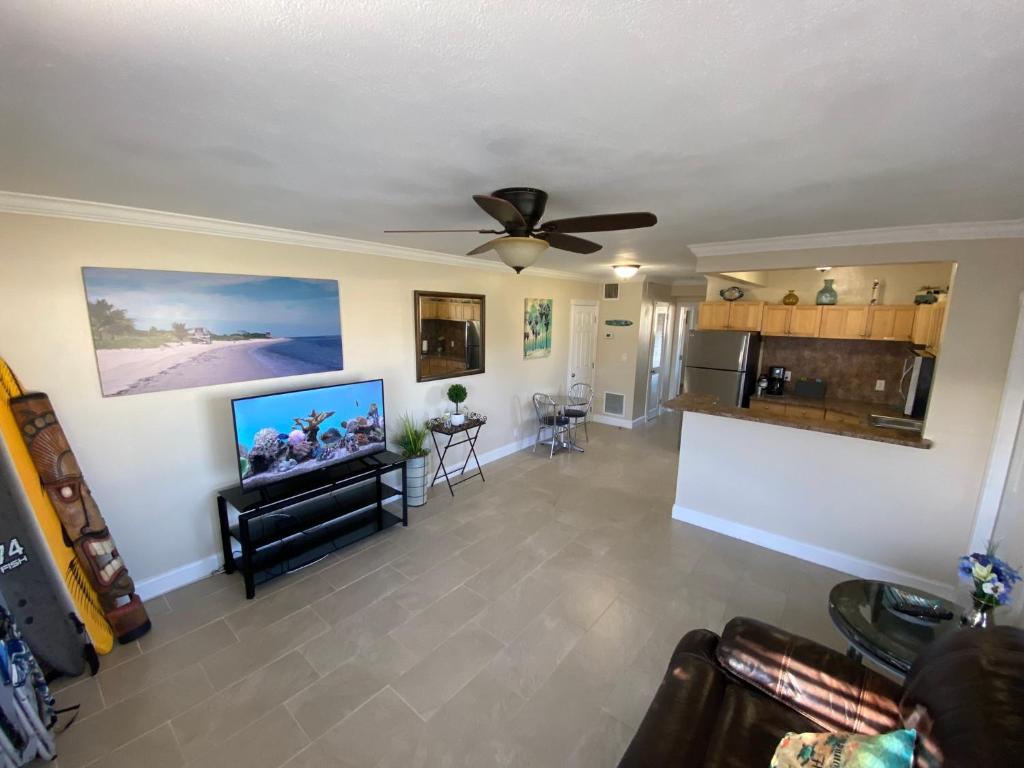 a living room with a ceiling fan and a tv at Visit Pomtuga and leave your worries behind in Pompano Beach