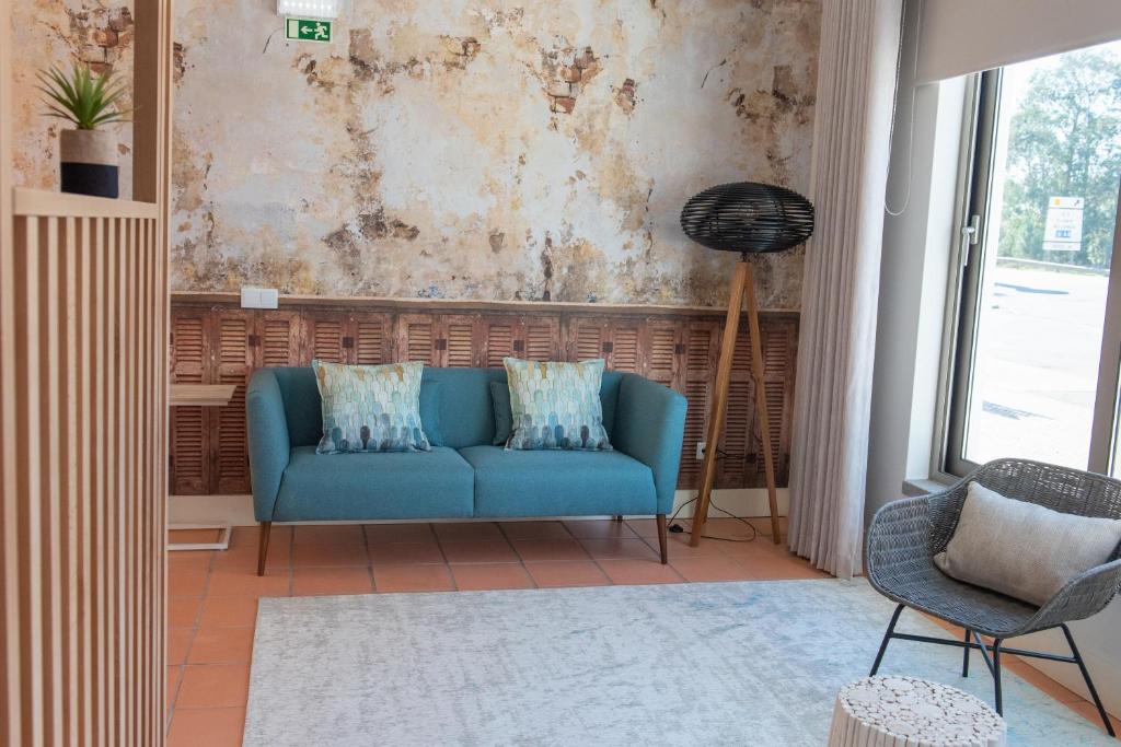 a living room with a blue couch and a window at Rota VMF - Alcobaça in Cruz da Légua