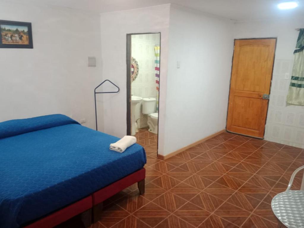 a bedroom with a blue bed and a bathroom at Habitación cerca aeropuerto in Calama