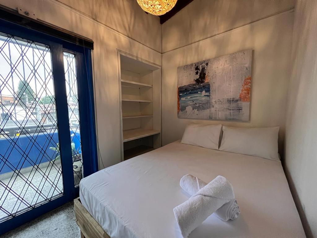 a bedroom with a bed and a large window at Hostal Casa Guadalupe in Medellín