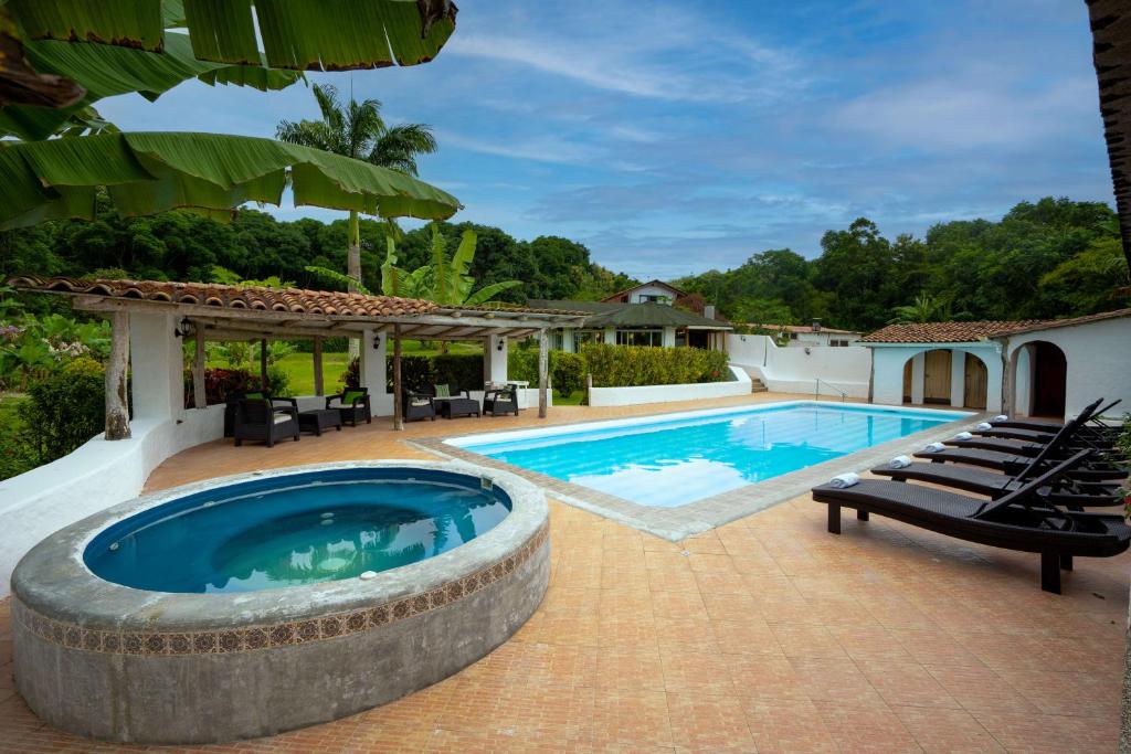 a swimming pool with chairs and a patio with a house at Enchanted Galapagos Lodge in Puerto Ayora