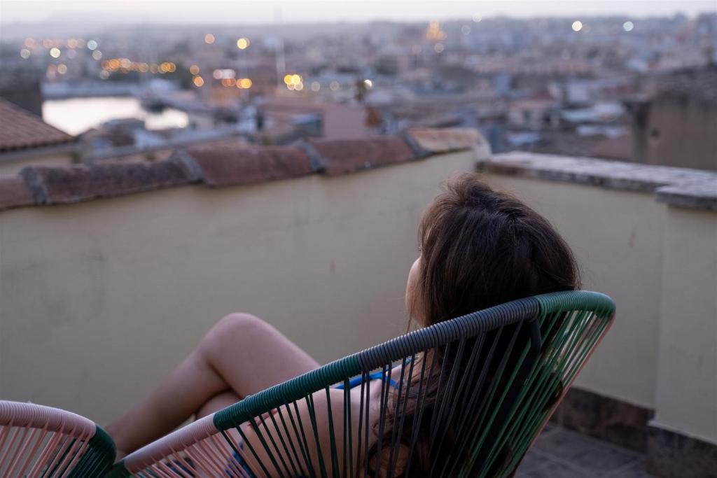 シラクーサにあるパラッツォ ジリストロの椅子に座って街を見下ろす女
