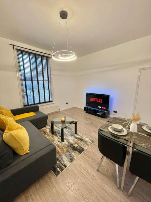 Spacious, Modern 2 Bed Apartment في لندن: غرفة معيشة مع أريكة وطاولة