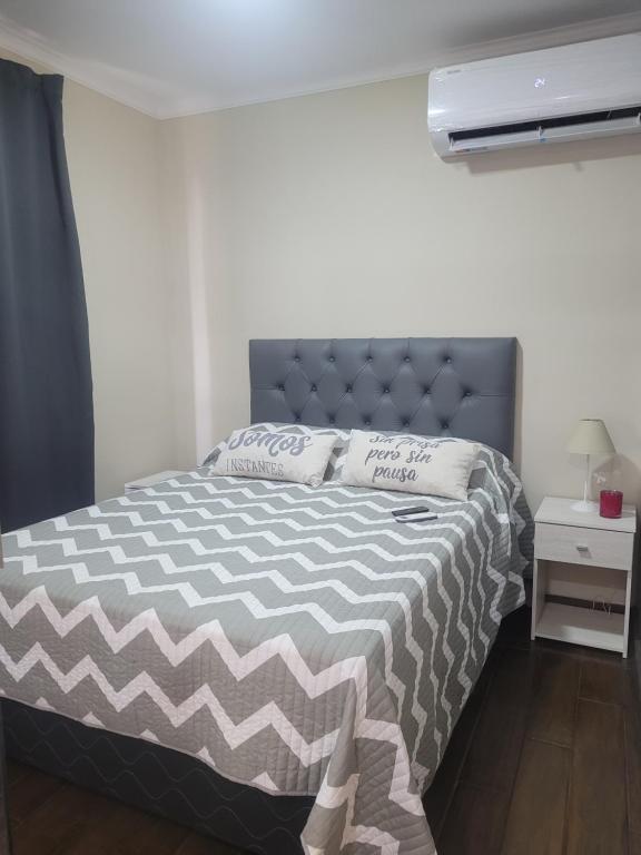 a bedroom with a bed with a gray and white comforter at Depto. Céntrico III in Corrientes