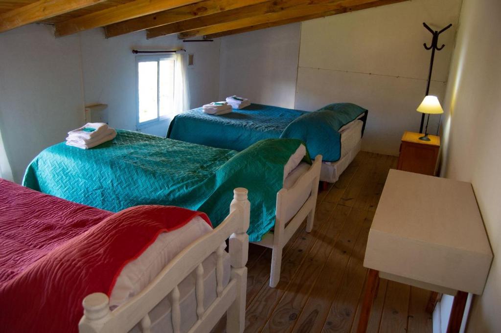 a bedroom with two beds and a table and a window at Los Ñires in Esquel