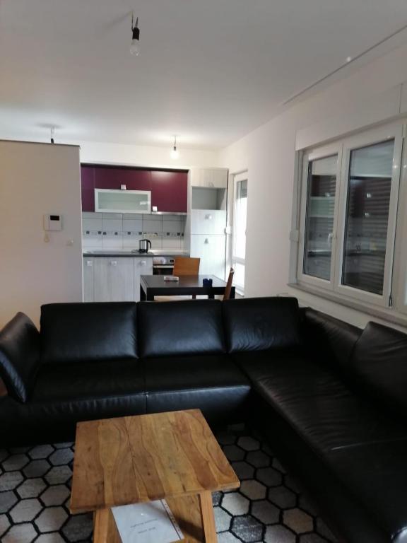 a living room with a black leather couch and a table at Delux Apartment in Sarajevo