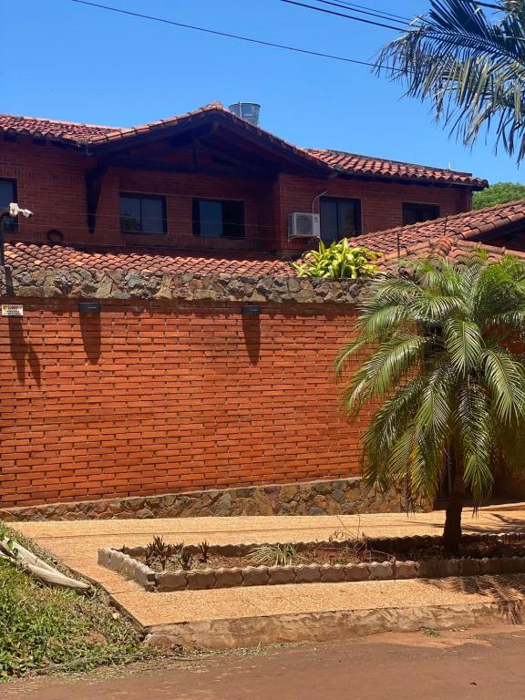 a brick wall with a palm tree in front of a house at Casa hotel in Encarnación