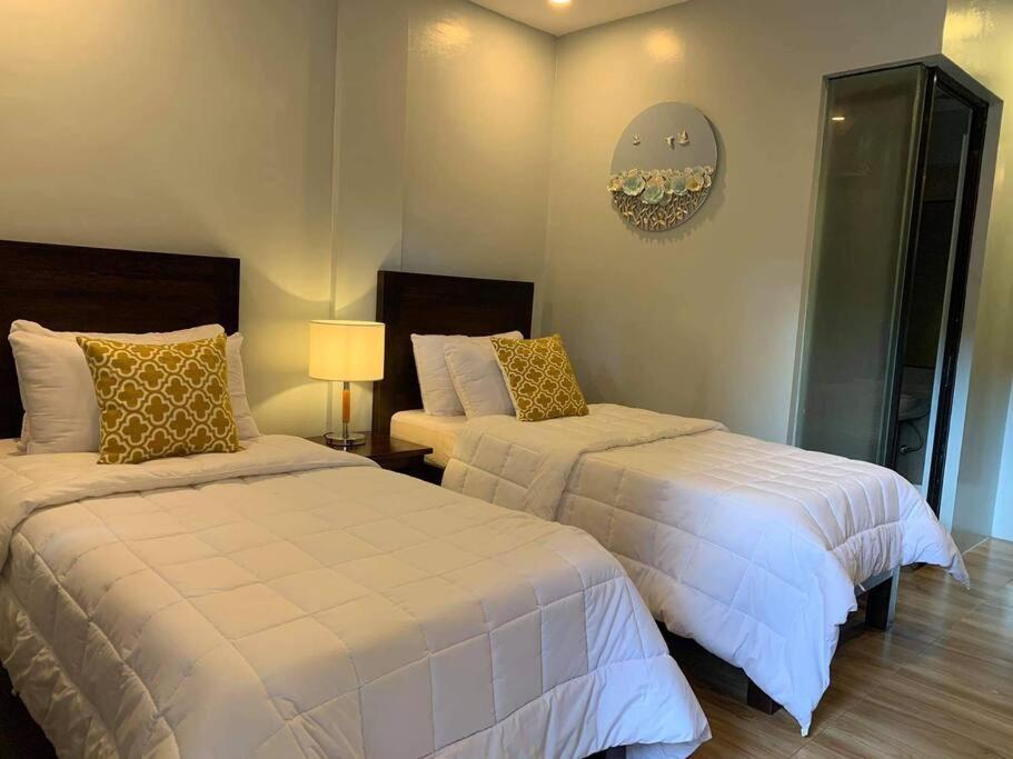 1 Schlafzimmer mit 2 Betten mit weißer Bettwäsche und einer Lampe in der Unterkunft The Great Molave FAMILY ROOM in Cavite