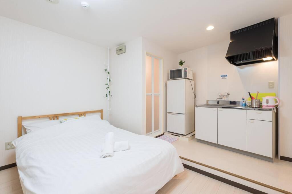 a bedroom with a white bed and a refrigerator at 難波南52 in Osaka