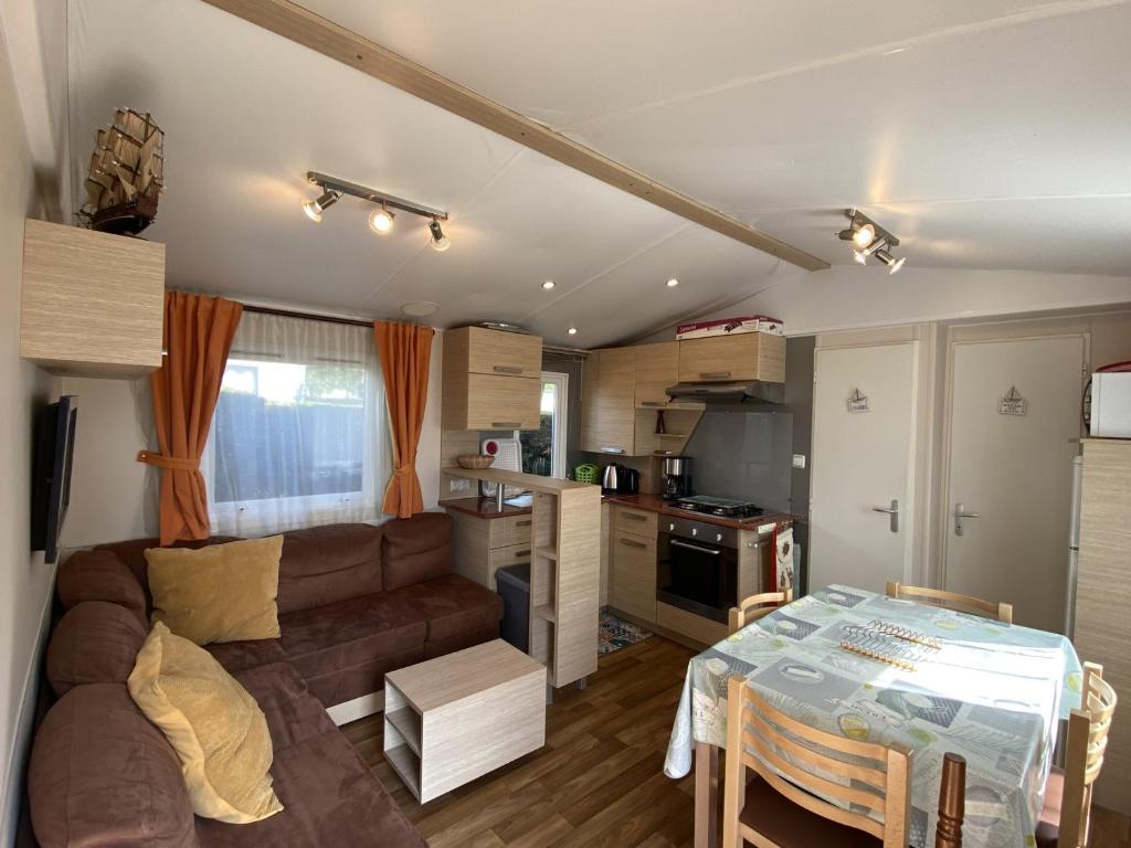salon i kuchnia z kanapą i stołem w obiekcie Mobil-home à Fouras : Proche Plage, 2 Chambres, TV, Plancha, Parking, Idéal Famille - FR-1-709-58 w mieście Fouras