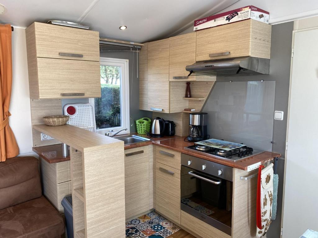 małą kuchnię z drewnianymi szafkami i kuchenką w obiekcie Mobil-home à Fouras : Proche Plage, 2 Chambres, TV, Plancha, Parking, Idéal Famille - FR-1-709-58 w mieście Fouras