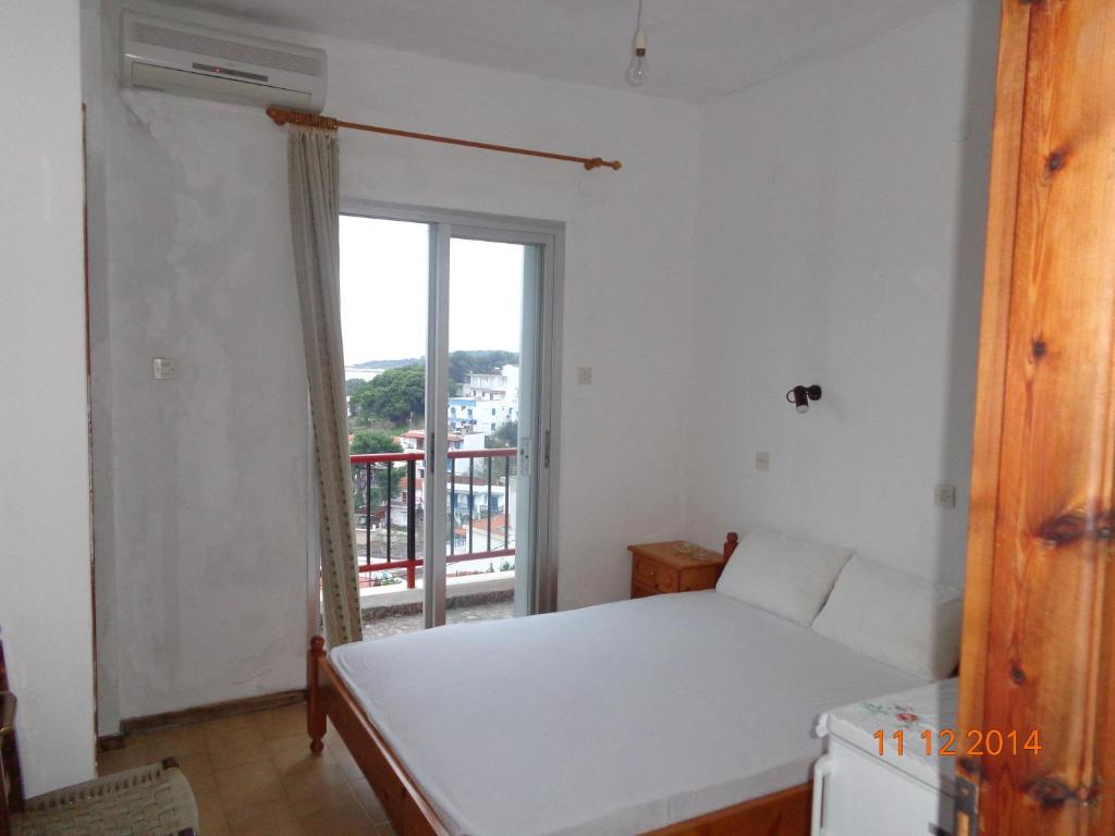 ein Schlafzimmer mit einem weißen Bett und einem Fenster in der Unterkunft George Rooms in Votsi