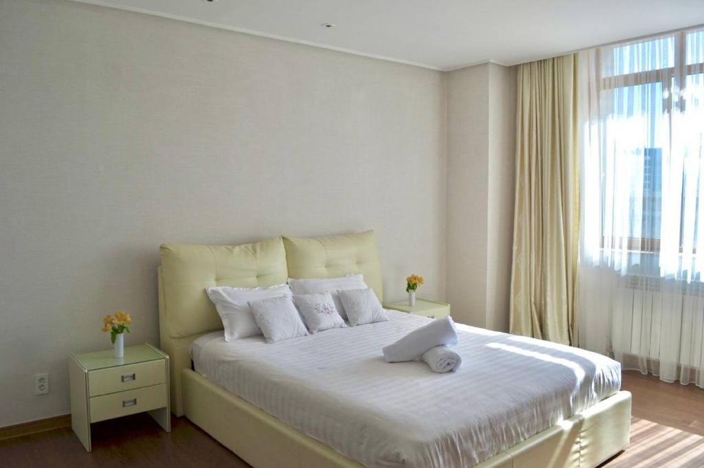 a bedroom with a large white bed with a window at HIGHVILL PARK in Taldykolʼ