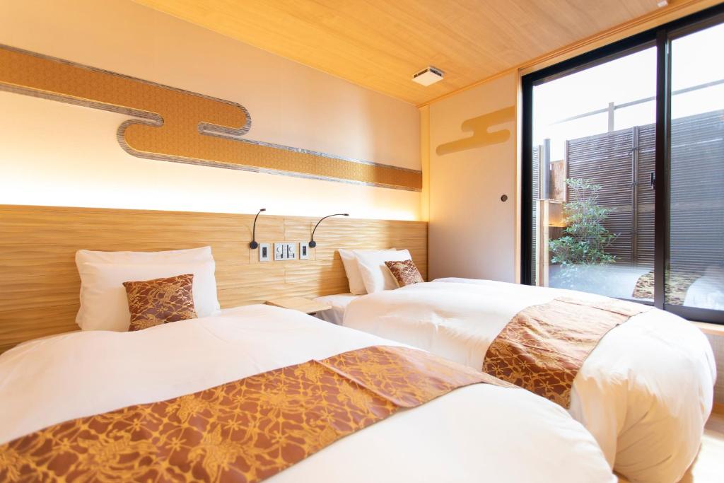 two beds in a room with a window at Higashiyama Hills in Kyoto