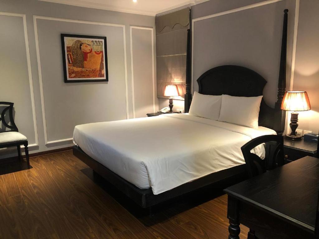 a bedroom with a bed and two tables and two lamps at Le Grand Hanoi Hotel - 18 Hàng Quạt by Bay Luxury in Hanoi