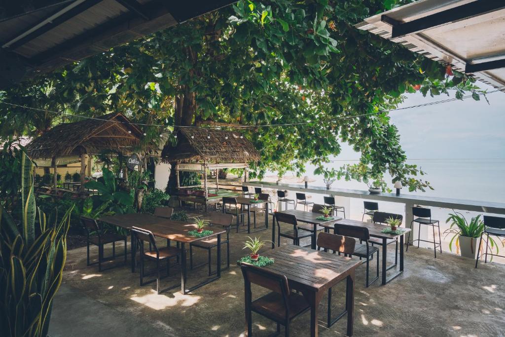 restauracja ze stołami i krzesłami pod drzewem w obiekcie Chill Inn Lamai Hostel & Beach Cafe w mieście Koh Samui