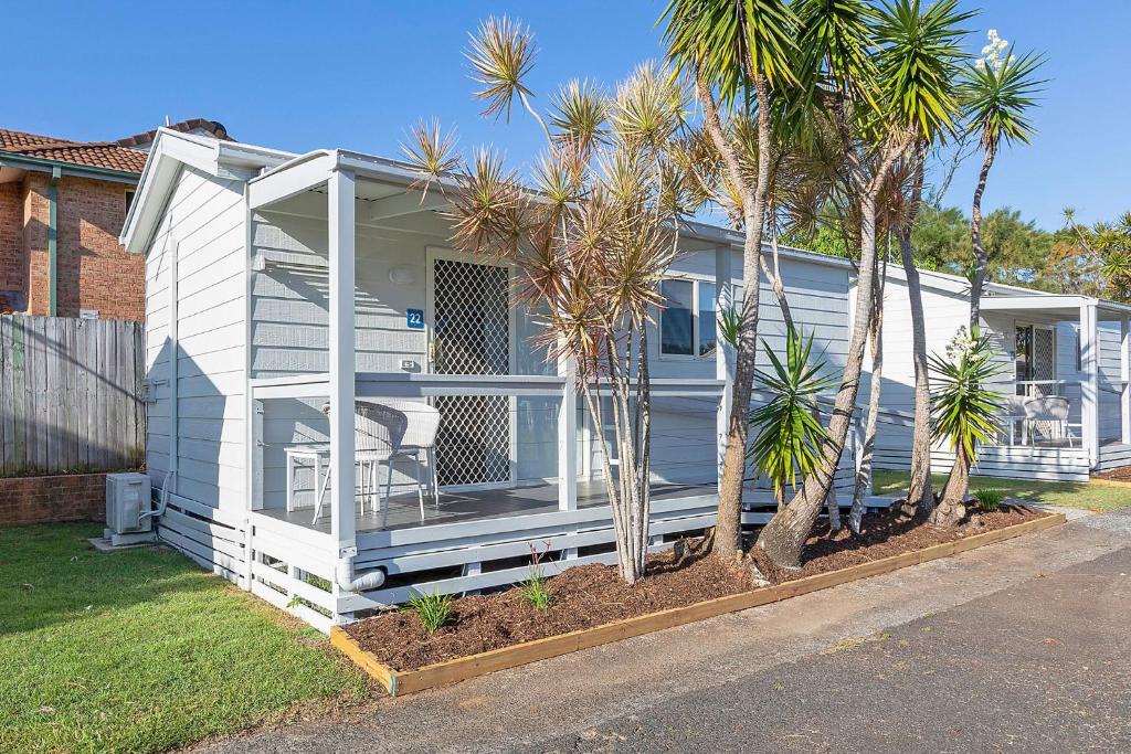 a white house with palm trees in front of it at Reflections Ballina - Holiday Park in Ballina