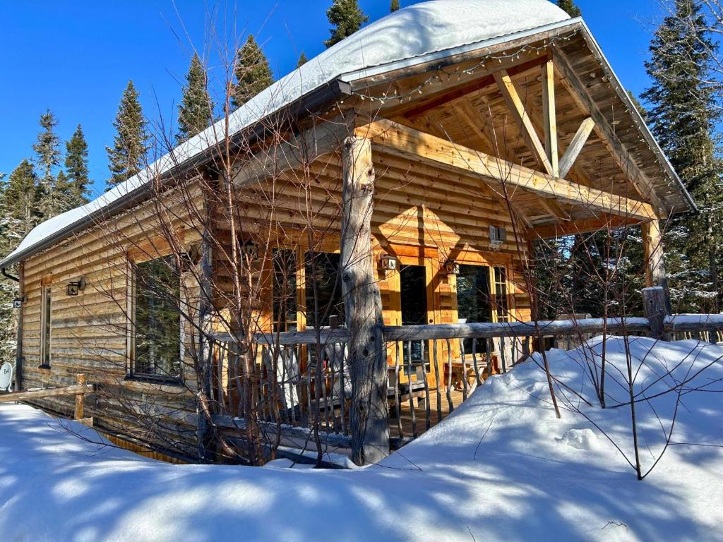 una cabaña de madera en la nieve en el bosque en HUSKY - Chalets de Môh - Jacuzzi en La Malbaie