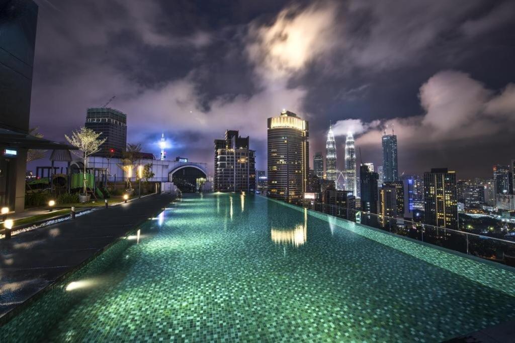 una piscina con vista sullo skyline della città di notte di Dorsett Residences Bukit Bintang a Kuala Lumpur