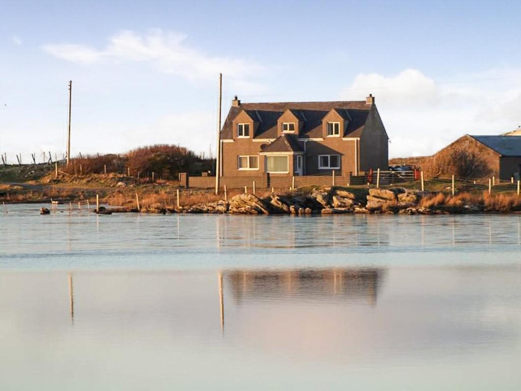 a house on the shore of a body of water at Maari in Trumisgarry