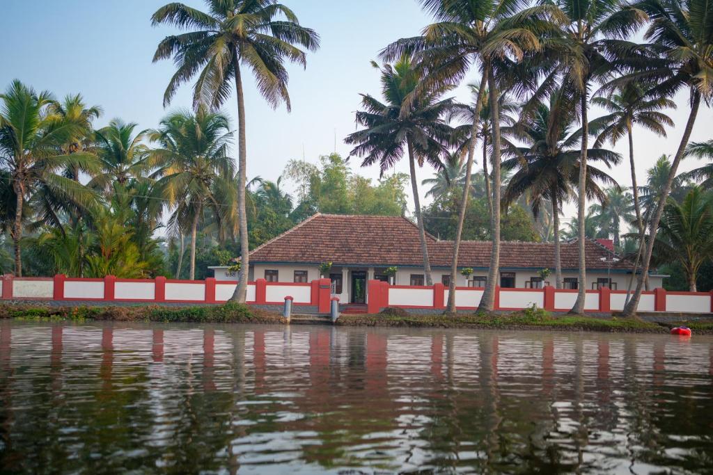 a house on the banks of a river with palm trees at Kuttanad Kayak Club by Lexstays in Alleppey