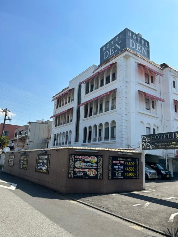 um edifício branco com um sinal na lateral em ホテルDEN em Tóquio