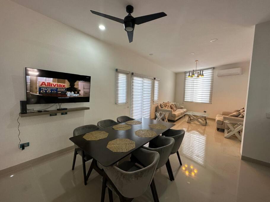 a dining room with a table and chairs and a flat screen tv at Departamento isla central 2 in Mazatlán