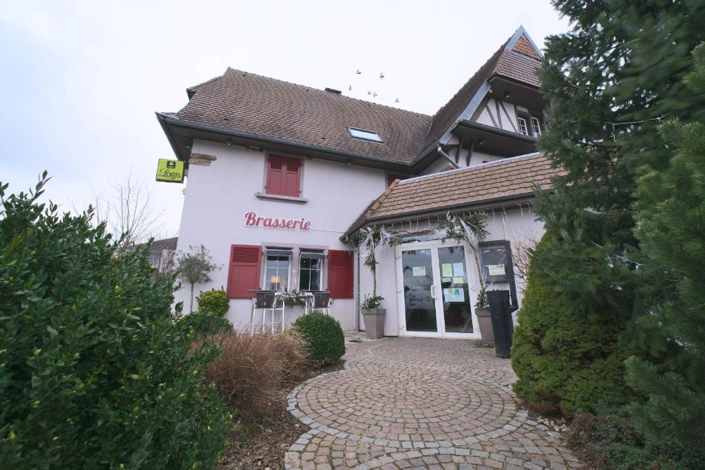 ein weißes Gebäude mit einer roten Tür und einem Gehweg in der Unterkunft Hôtel Restaurant Au Lion d'Or in Burnhaupt-le-Haut