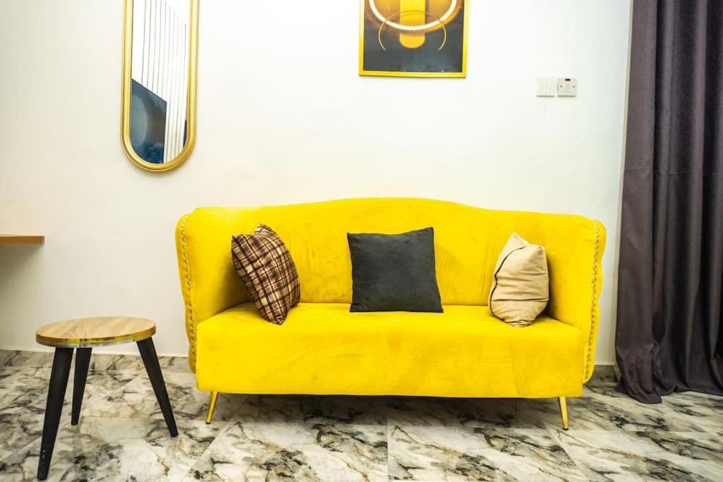 ein gelbes Sofa im Wohnzimmer mit Kissen darauf in der Unterkunft Elegant 1-Bed With Unlimited Internet + 24hrs POWER in Lagos