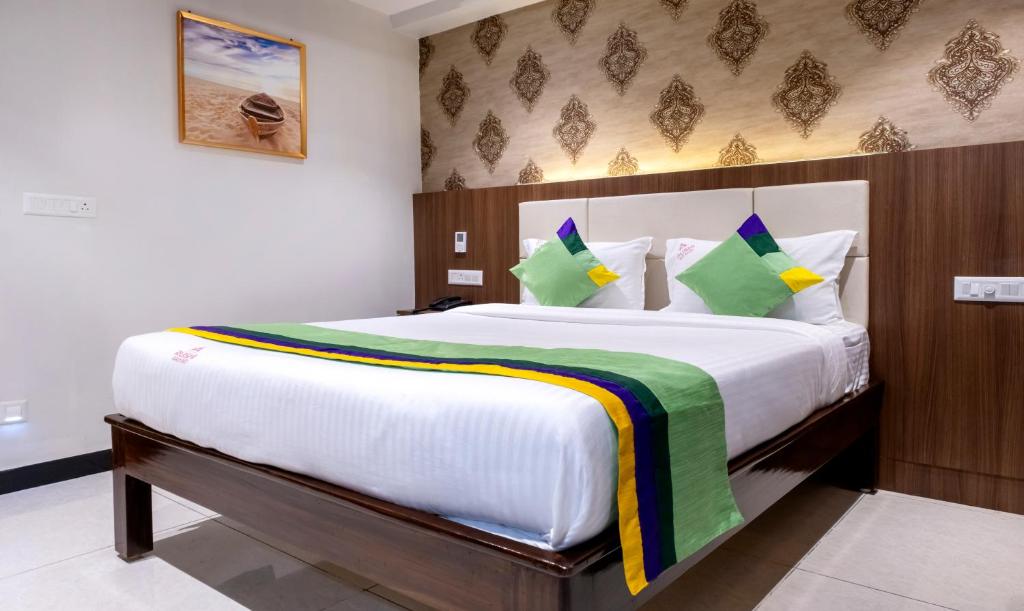 a bedroom with a large white bed with green and yellow pillows at Treebo Rushi Grand, 1 km to Rushikonda Beach in Visakhapatnam