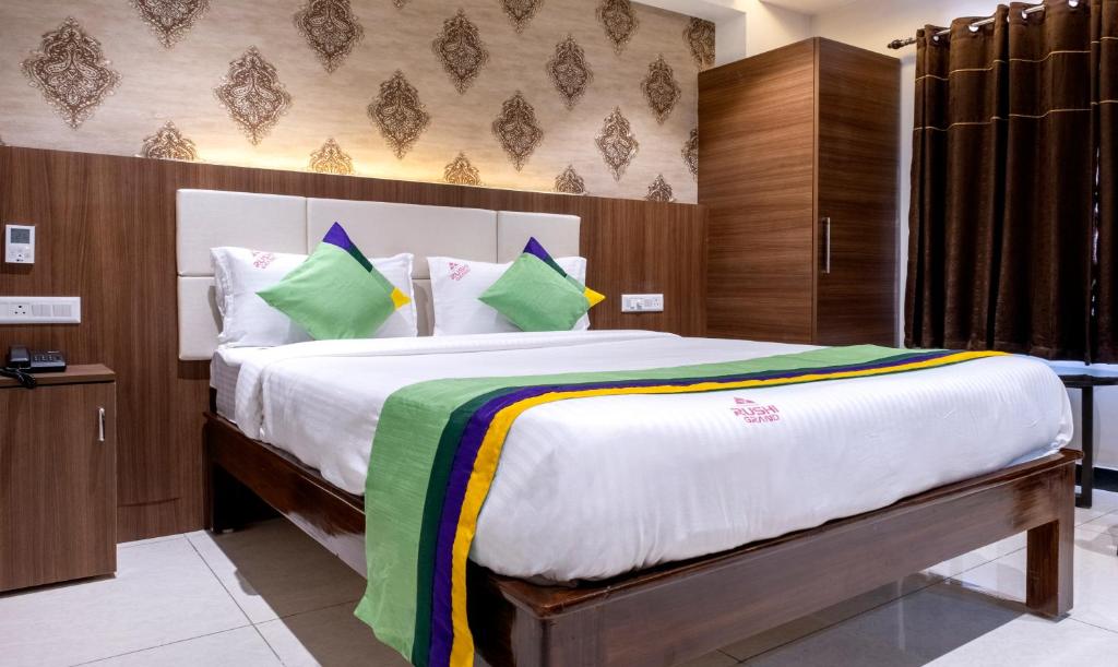 a bedroom with a large white bed with green pillows at Treebo Trend Rushi Grand in Visakhapatnam