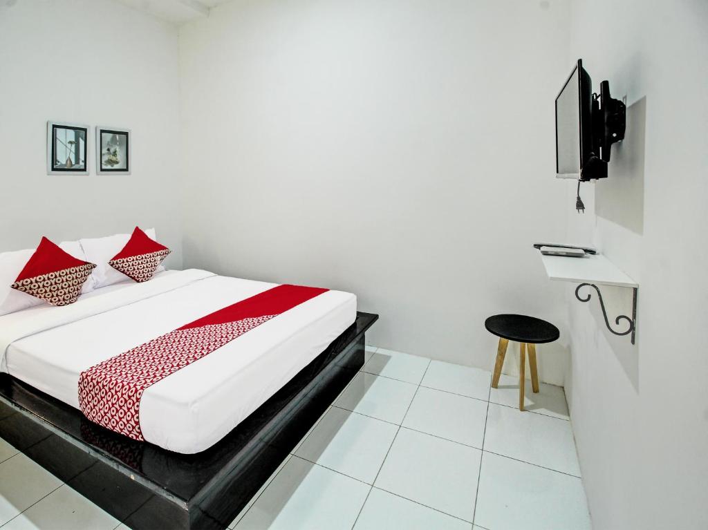 1 dormitorio con cama con almohadas rojas y taburete en Super OYO 92433 Sirih Gading Family Guest House en Tulungagung