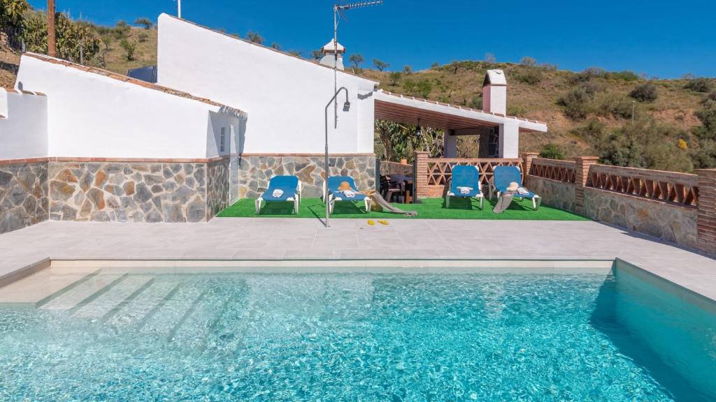 een zwembad met twee stoelen en een huis bij Casa Elena de Benagalbon Rincon de la Victoria by Ruralidays in Rincón de la Victoria