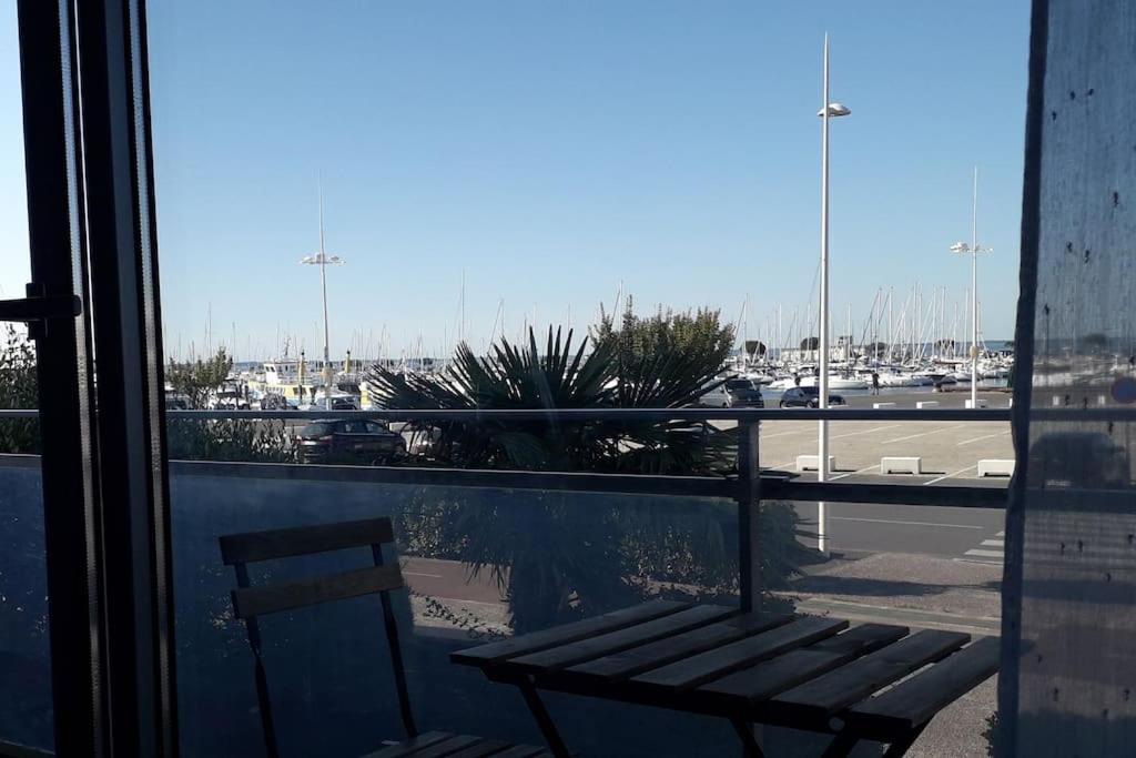 un banc installé à l'extérieur d'une fenêtre avec vue sur un parking dans l'établissement Appartement sur le port d'Arcachon proche plages, à Arcachon