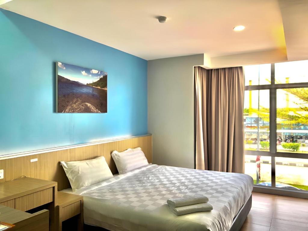 1 dormitorio con 1 cama con pared azul en Double Happiness Hotel en Seri Manjung