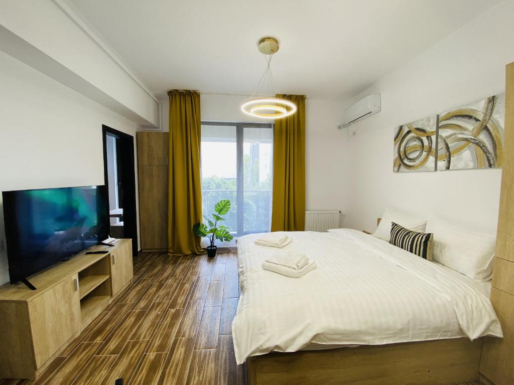 a bedroom with a large bed and a flat screen tv at New City Studios with Balcony in Bucharest