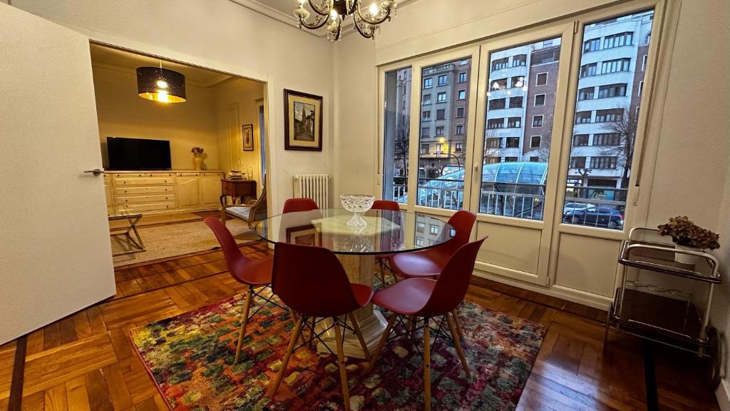ein Esszimmer mit einem Glastisch und roten Stühlen in der Unterkunft Fantástico apartamento en el centro de Bilbao in Bilbao