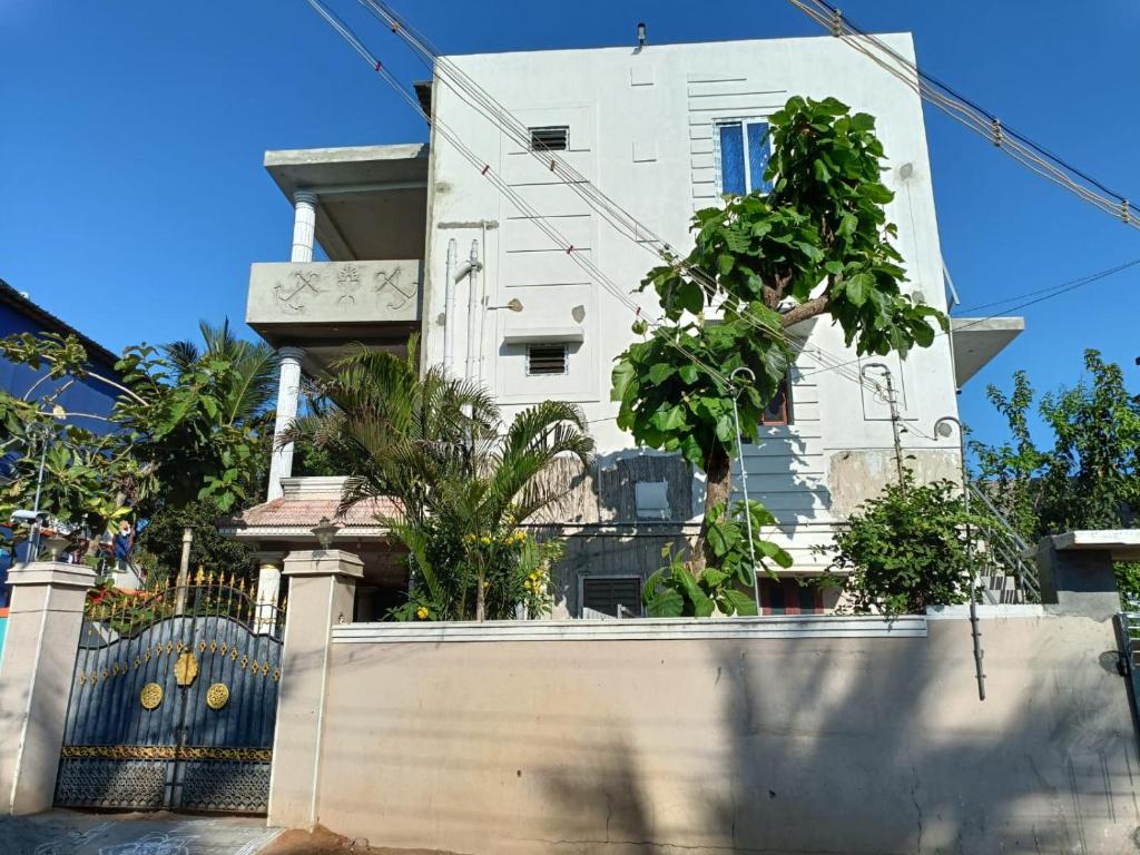 une maison blanche avec une clôture devant elle dans l'établissement Blue Leaf Residency, à Rameswaram