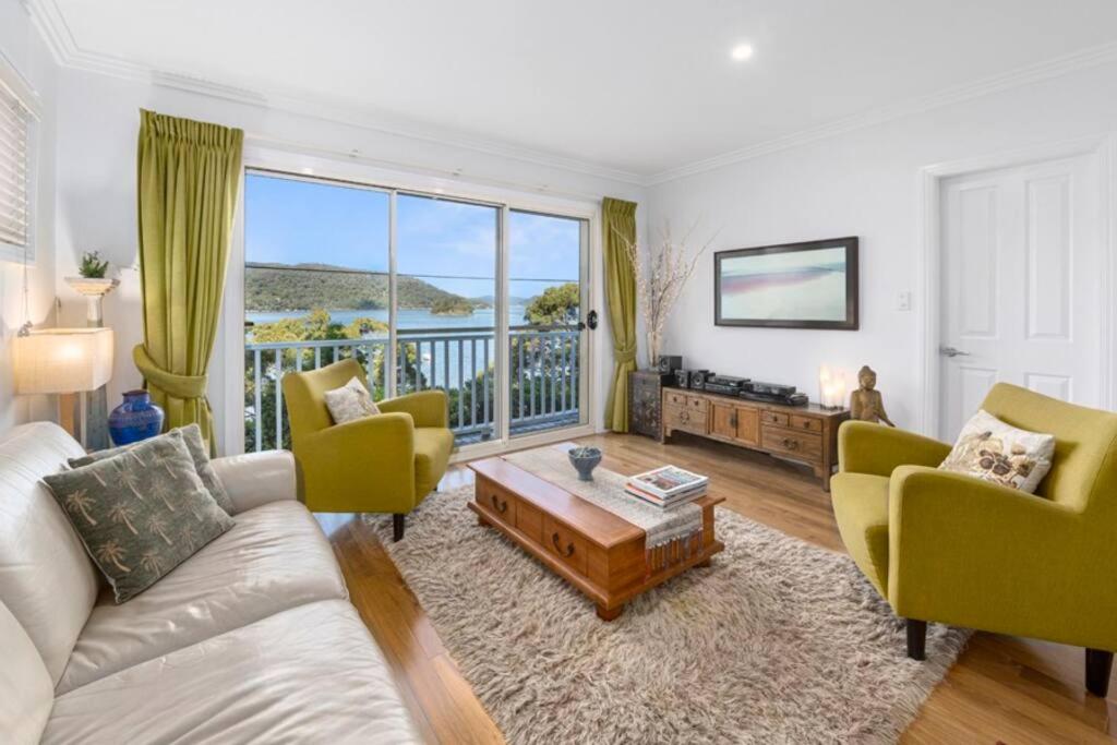 a living room with a couch and chairs and a large window at Cosy Cottage Above the Hawkesbury w/ Jetty in Mooney Mooney