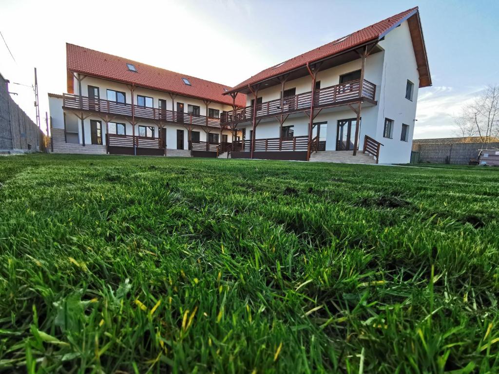 a building with a grass field in front of it at Bobocel Villa in Sfântu Gheorghe