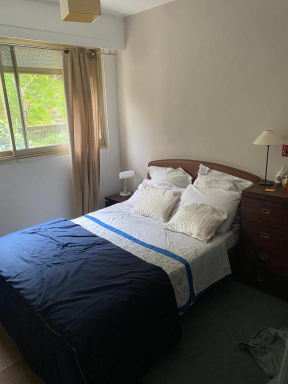 a bedroom with a bed with a blue blanket and a window at Une terrasse sur Monaco logement 2 chambre in Beausoleil