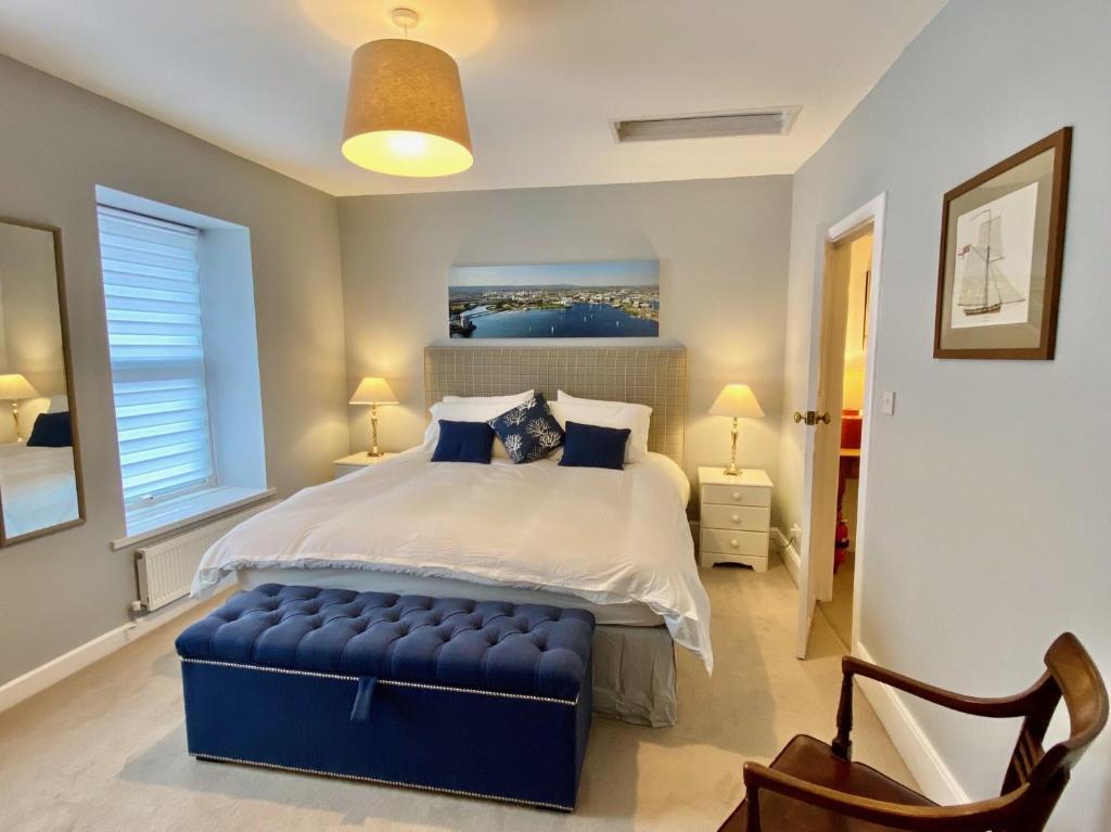 a bedroom with a large bed with a blue ottoman at Skipper’s Cottage - Perfect for Cardiff & Penarth in Cardiff