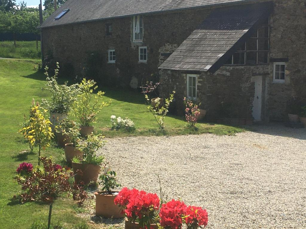 une ancienne maison en pierre avec des fleurs devant elle dans l&#39;établissement Chez Thomas 7 Route du Monde Ancien, à Saint-Georges-dʼAunay