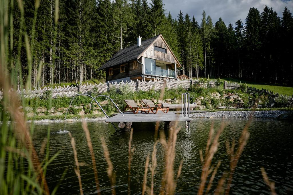 ein Haus, das auf einem Dock inmitten eines Sees liegt in der Unterkunft Heselehof Waldchalets in Langenwang