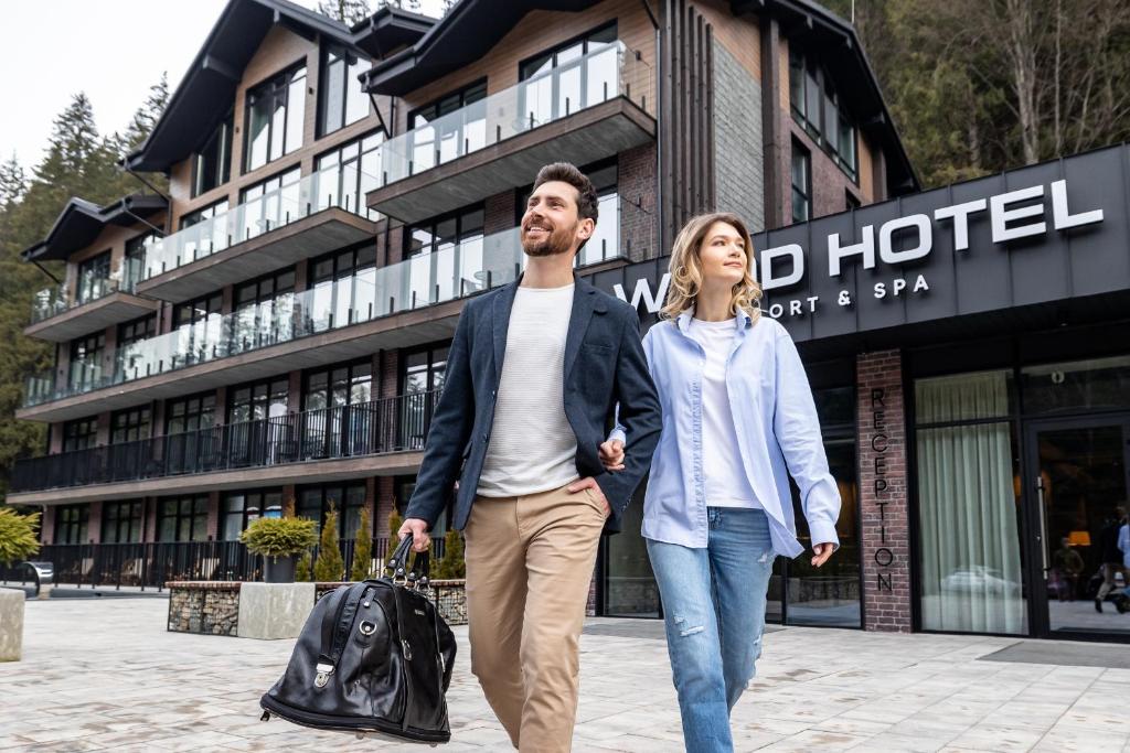 Un uomo e una donna che camminano davanti a un hotel di Wood Hotel Resort & SPA a Bukovel