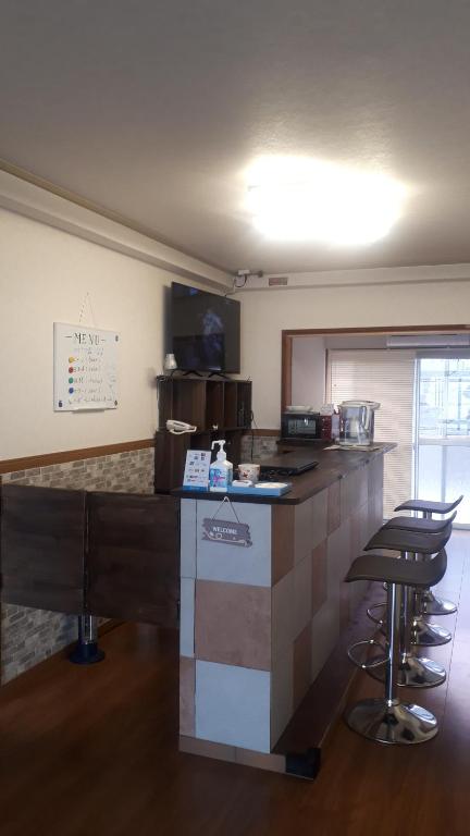 eine Küche mit einer Theke und einigen Barhockern in der Unterkunft ゲストハウスのスタジオ５１ in Sasebo