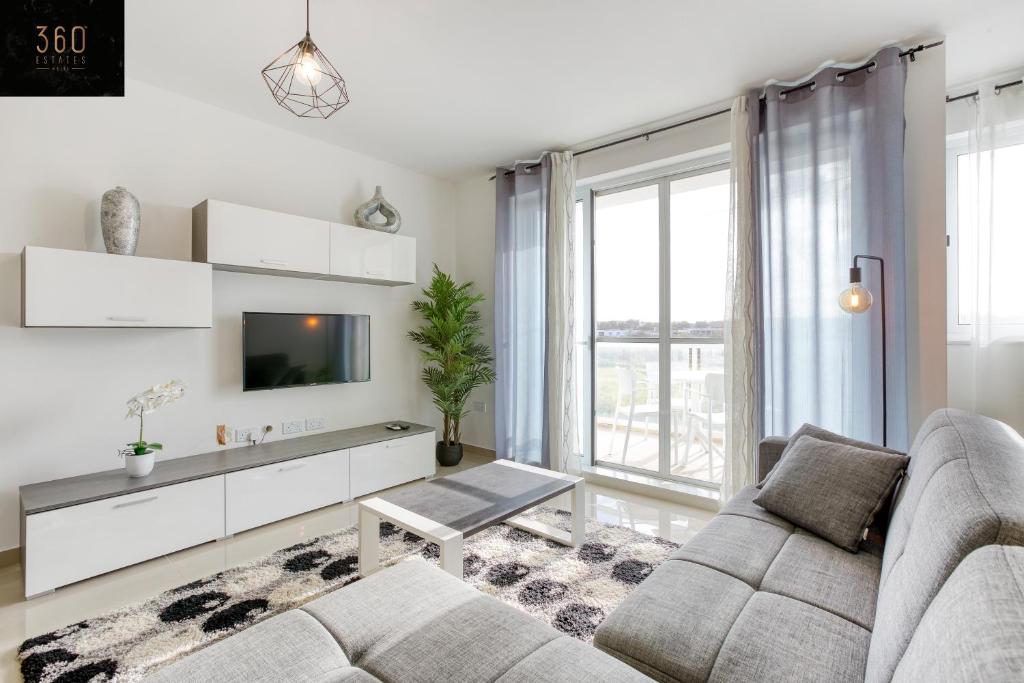 uma sala de estar com um sofá e uma televisão em Stunning 3BR w/Country View Apartment in M'Scalak by 360 Estates em Marsaskala